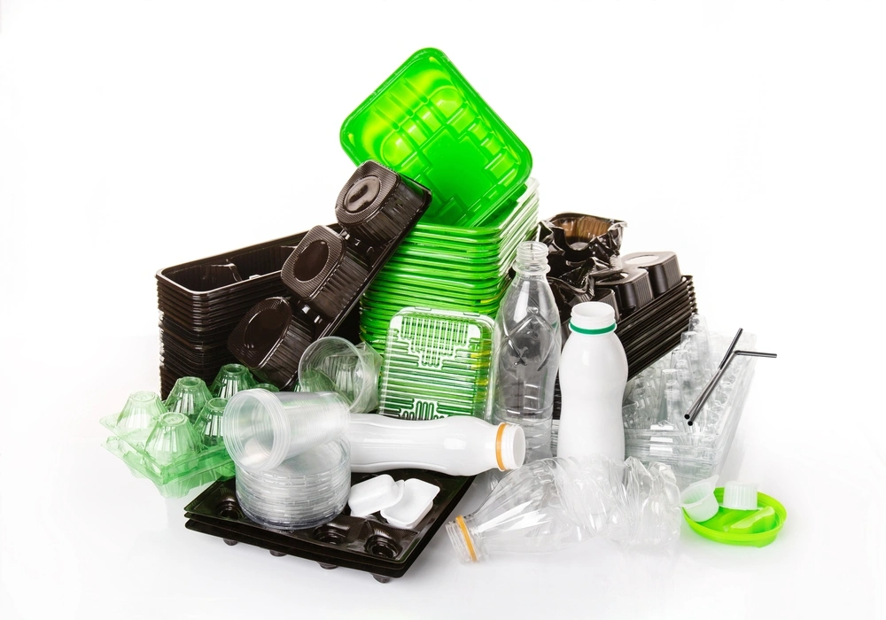 Clear, black, and green plastic food containers and bottles stacked together.